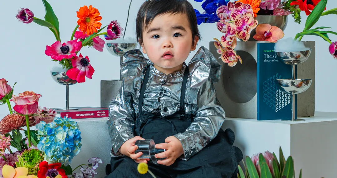 色とりどりの花に囲まれて座るベビー＆キッズ撮影の子ども