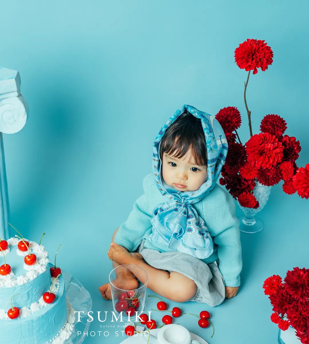 水色の背景で赤い花とともに写る赤ちゃん（Cherry シーン）