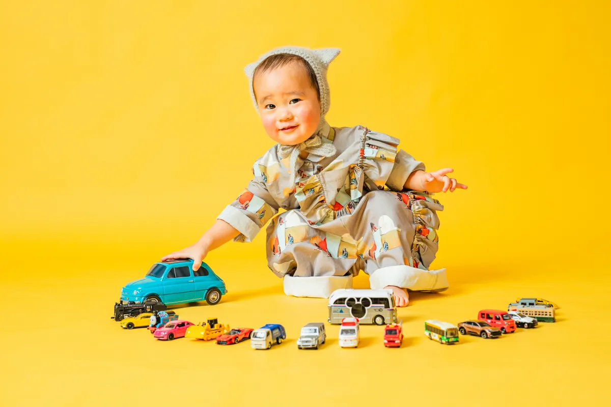 黄色い背景でミニカーを並べて遊ぶ子ども（Classic Portrait シーン）