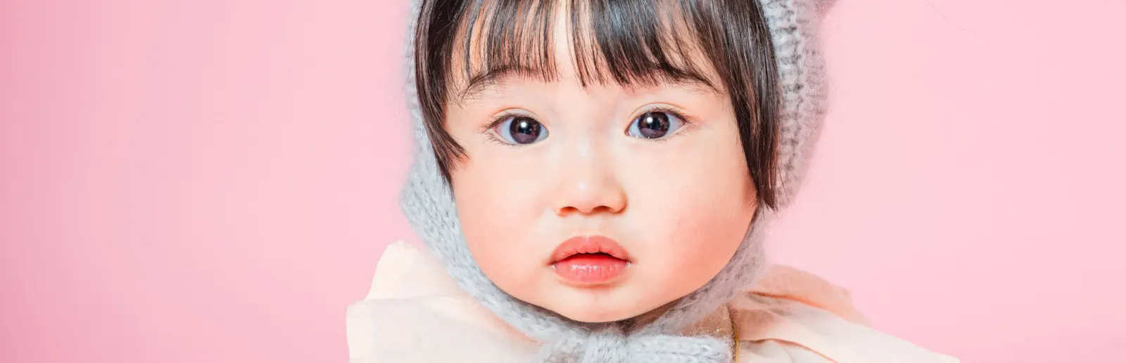 ピンク背景でボンネットをかぶった赤ちゃんのポートレート（Classic Portrait シーン）