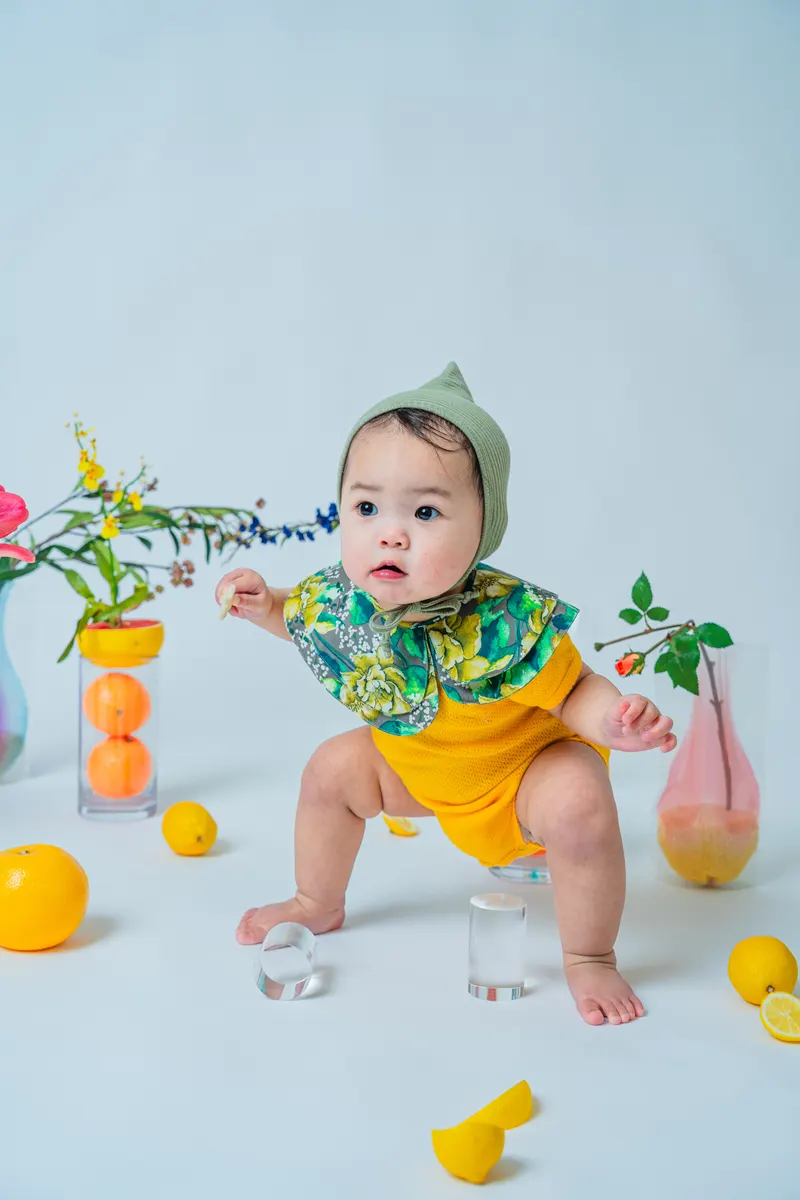 果物と花を背景に黄色い衣装で過ごす赤ちゃん（Fruit シーン）