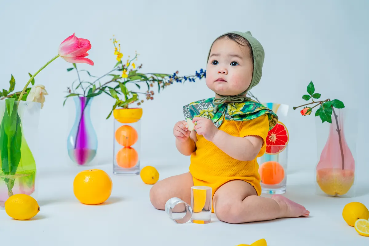 透明感のある果物と花に囲まれた黄色い衣装の赤ちゃん（Fruit シーン）