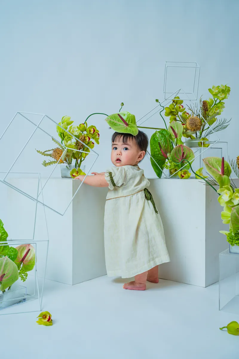 緑のアンスリウムと蘭に囲まれて立つ赤ちゃん（Garden シーン）