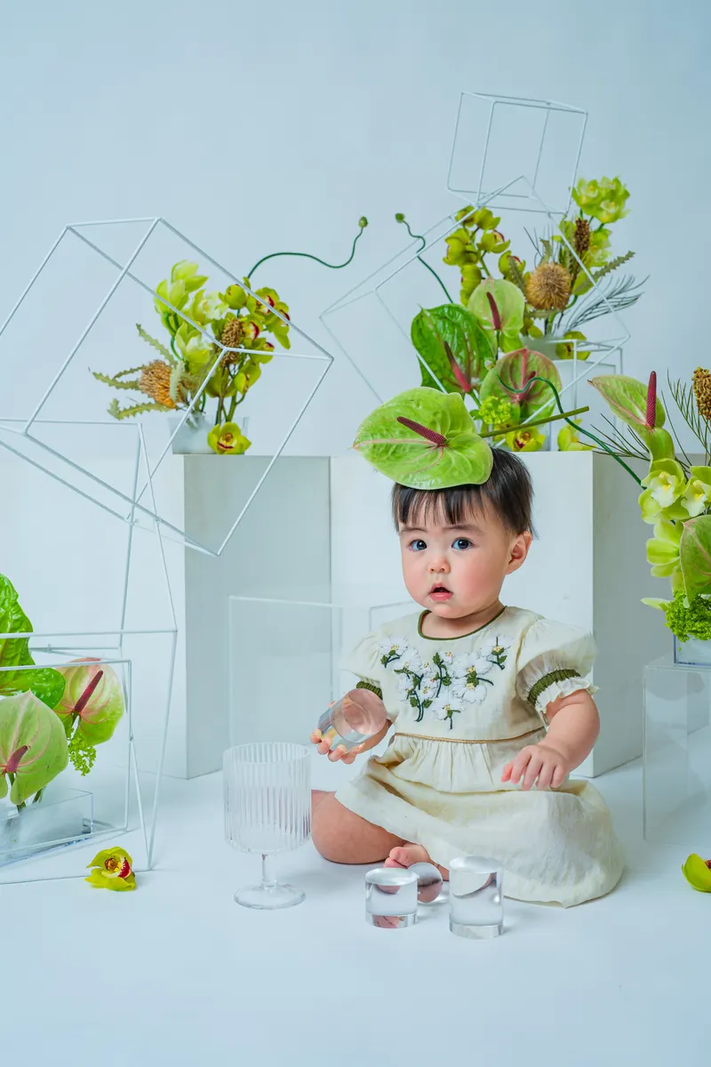 頭に緑の葉をのせてグラスで遊ぶ赤ちゃん（Garden シーン）