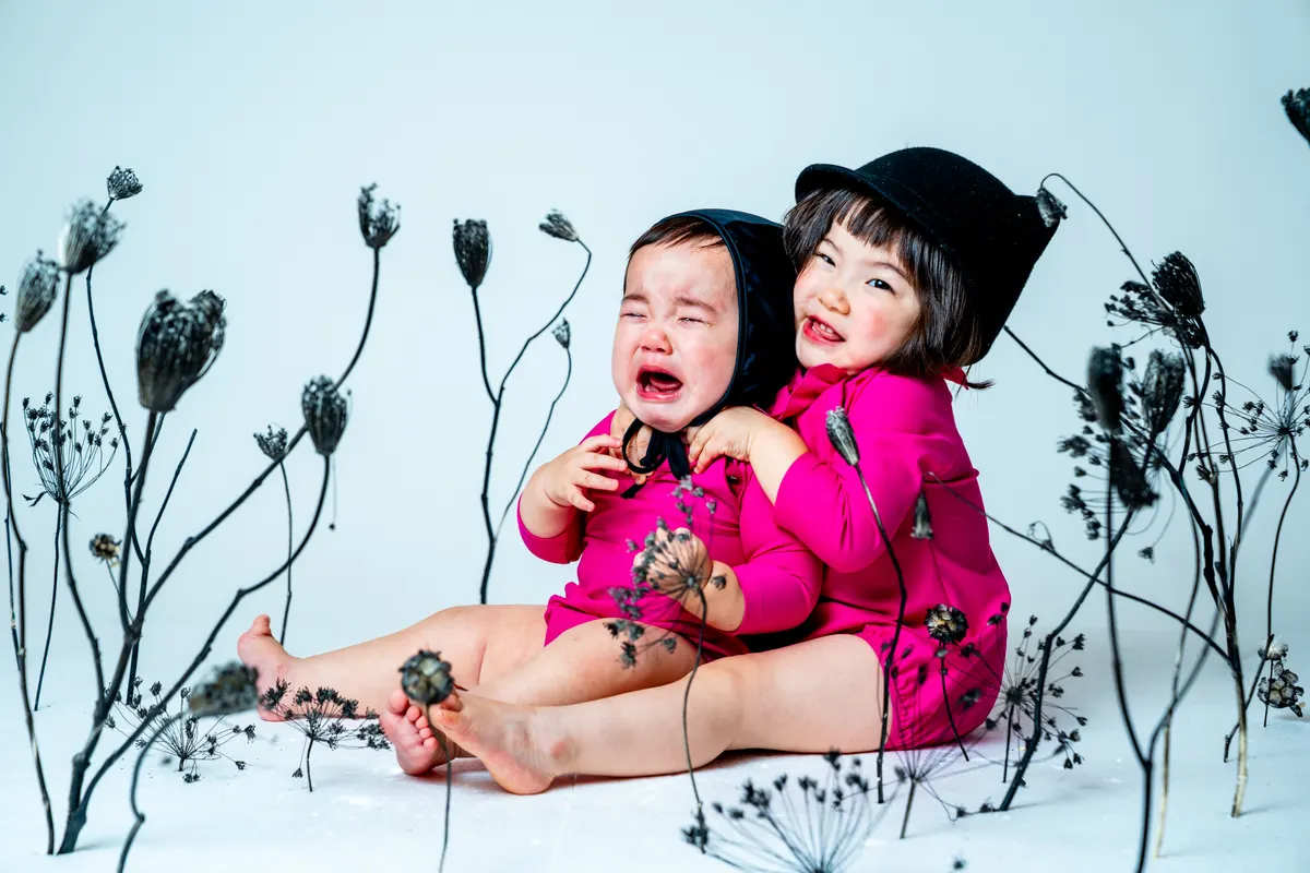 黒い枝花に囲まれて静かに写る子ども（Sumikuro シーン）