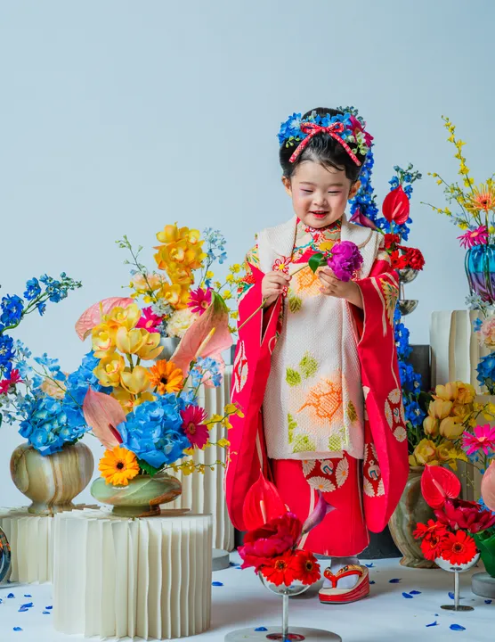 紅色地に鶴柄の着物に白い被布を合わせた「紅鈴」を着た子ども