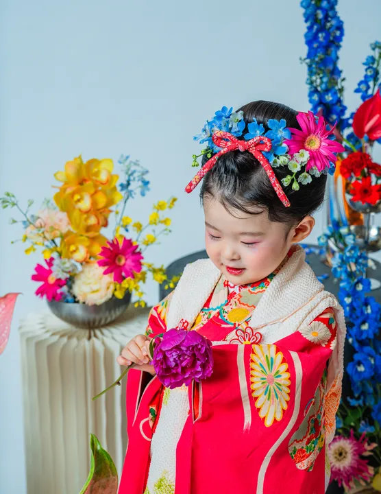 紅色地に鶴柄の着物に白い被布を合わせた「紅鈴」を着た子ども