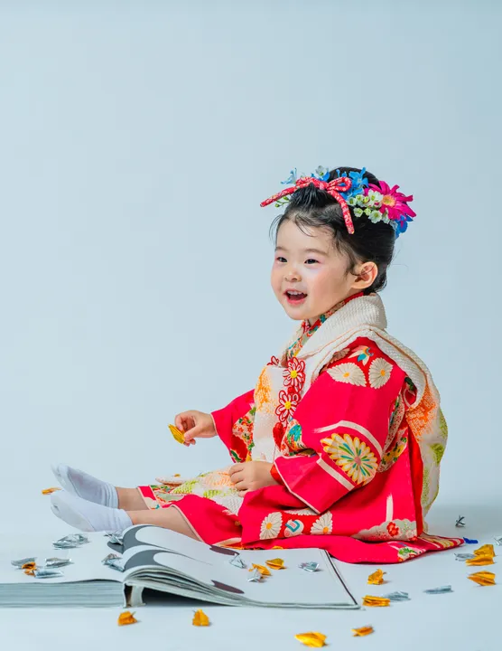 紅色地に鶴柄の着物に白い被布を合わせた「紅鈴」を着た子ども
