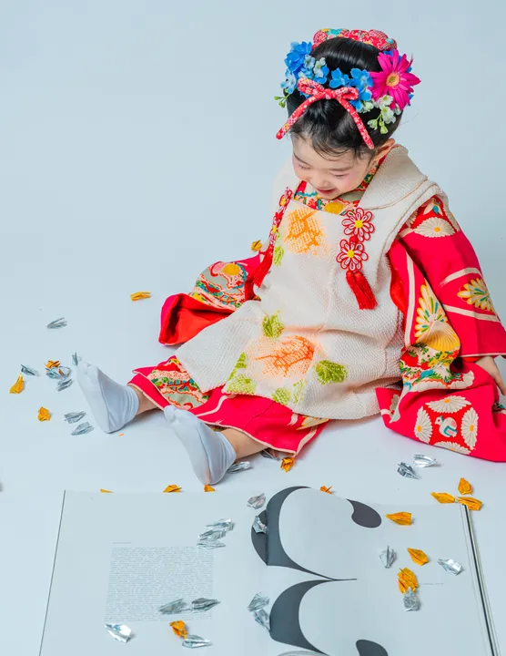 紅色地に鶴柄の着物に白い被布を合わせた「紅鈴」を着た子ども