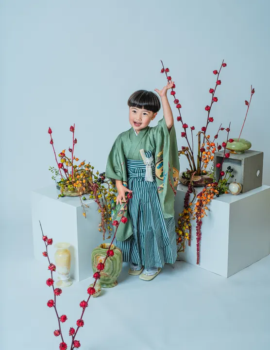 くすみグリーンの羽織に縞袴を合わせた着物「矢羽」を着た男の子