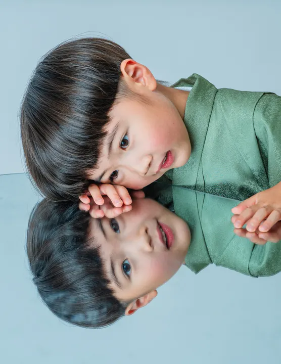 くすみグリーンの羽織に縞袴を合わせた着物「矢羽」を着た男の子