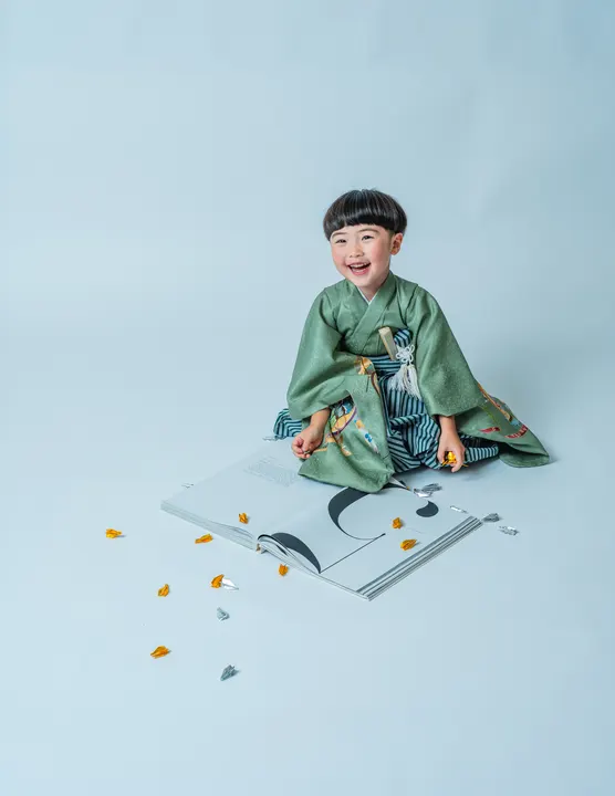 くすみグリーンの羽織に縞袴を合わせた着物「矢羽」を着た男の子