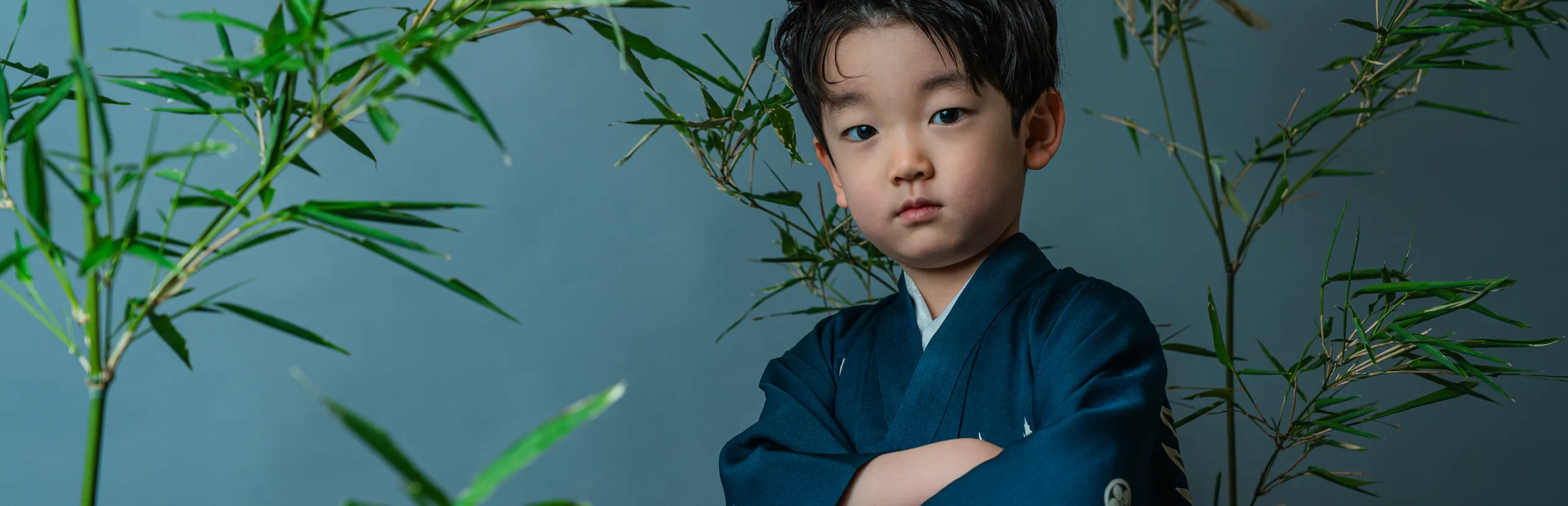 青い着物で腕を組み竹に囲まれて立つ七五三の男の子（Chikurin シーン）