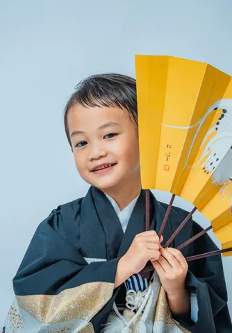 鳥が描かれた扇子を手にする羽織袴姿の七五三の男の子(Engimono シーン)