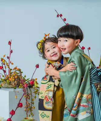 花飾りを前に抱き合って笑う着物姿の七五三の姉弟(kyoudai シーン)