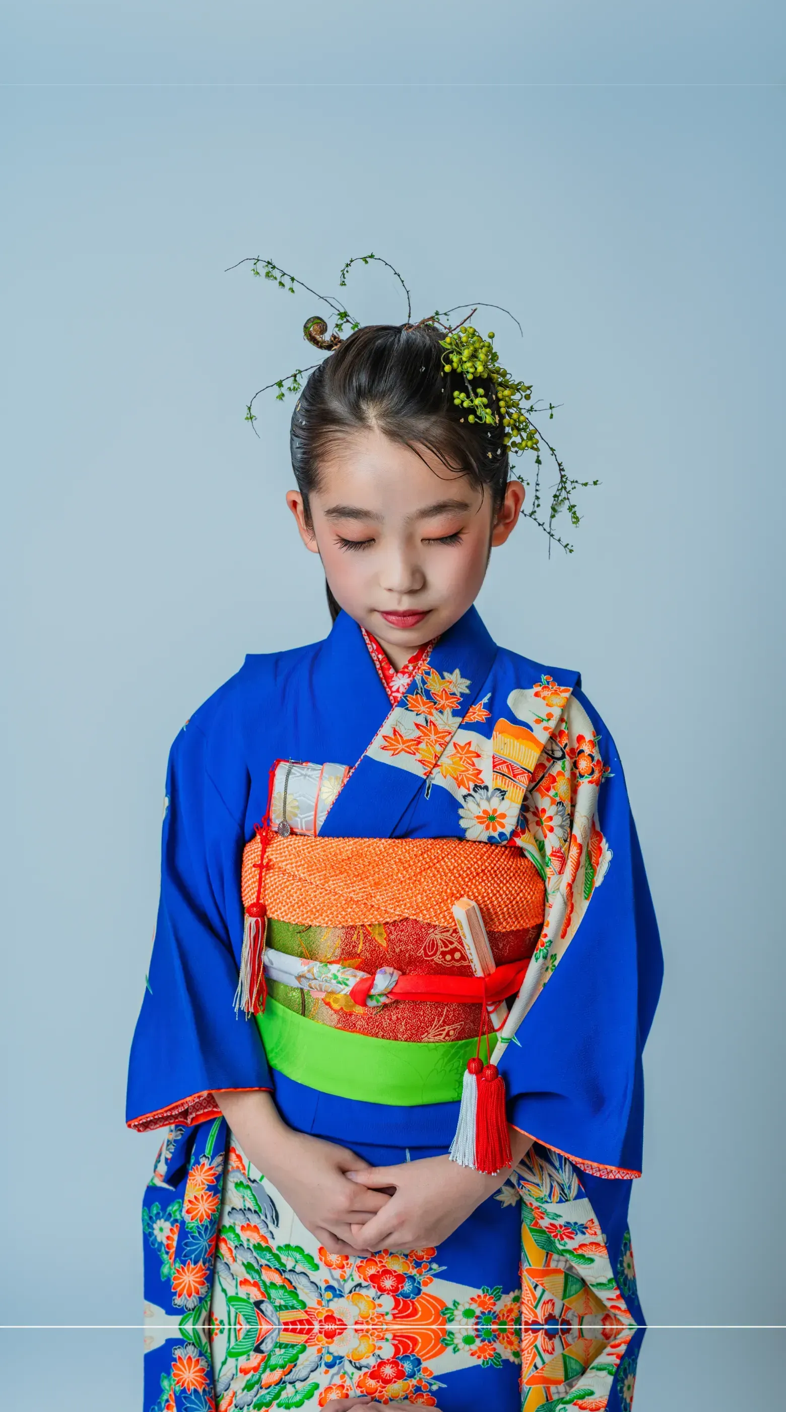 青い着物に橙色の帯を締めた七五三の女の子