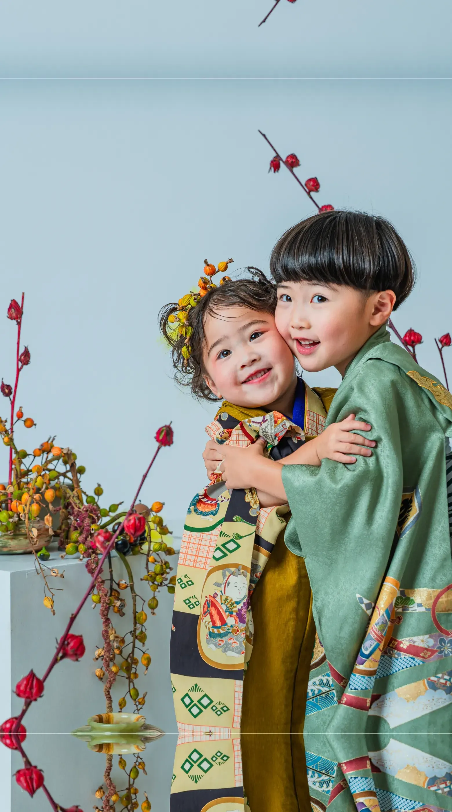 花飾りを前に抱き合う着物姿の七五三の姉弟