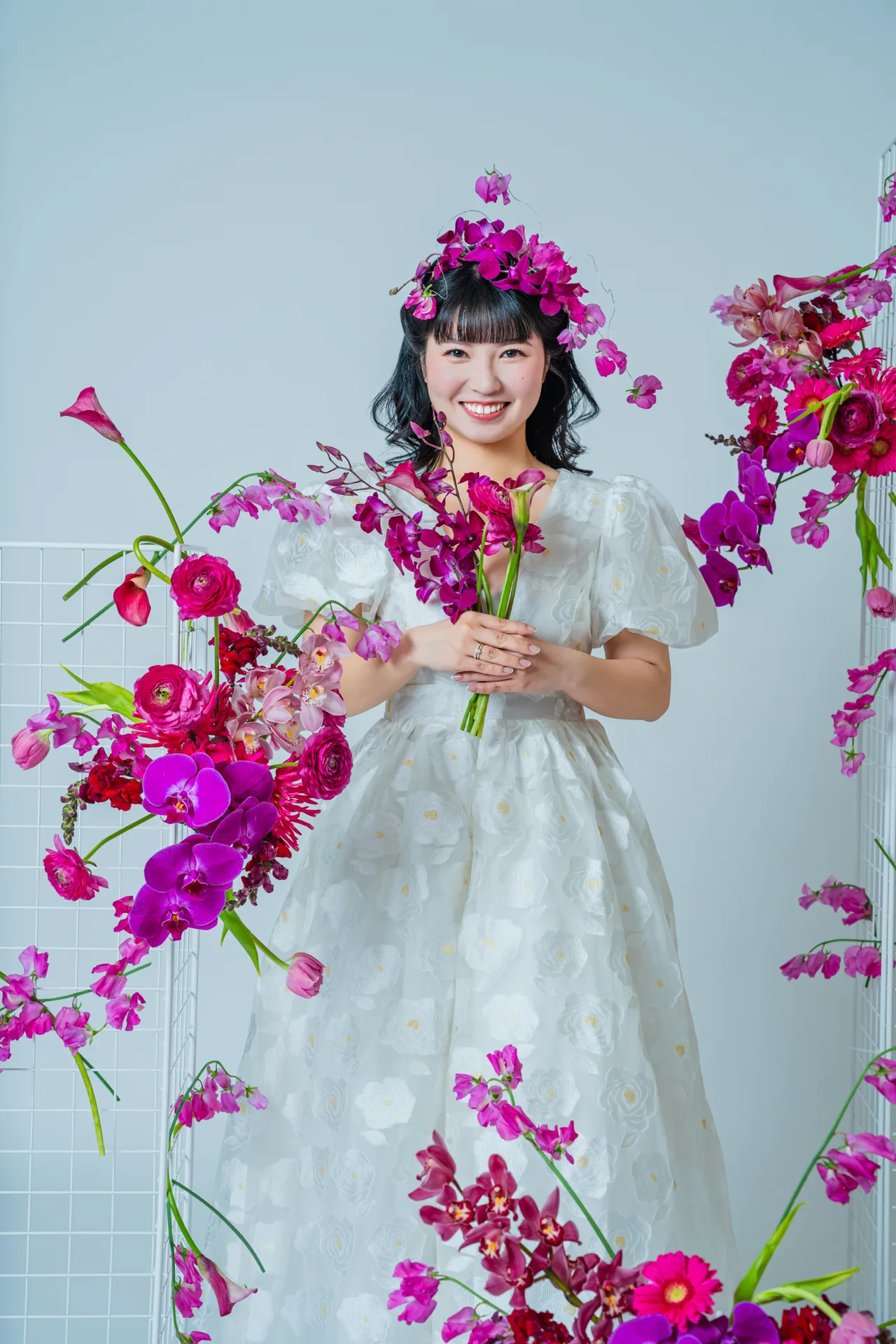 鮮やかな生花に囲まれて花束を抱える白いドレス姿の花嫁