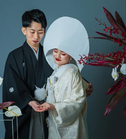 綿帽子に白無垢の花嫁と寄り添う黒紋付の新郎(和装シーン)