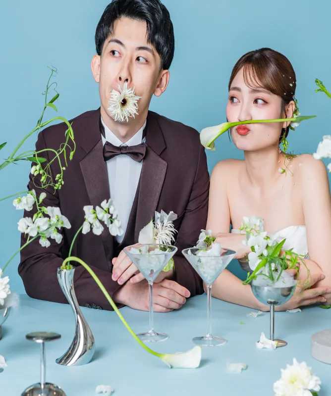 花を口元にあてておどける新郎新婦(Table シーン)