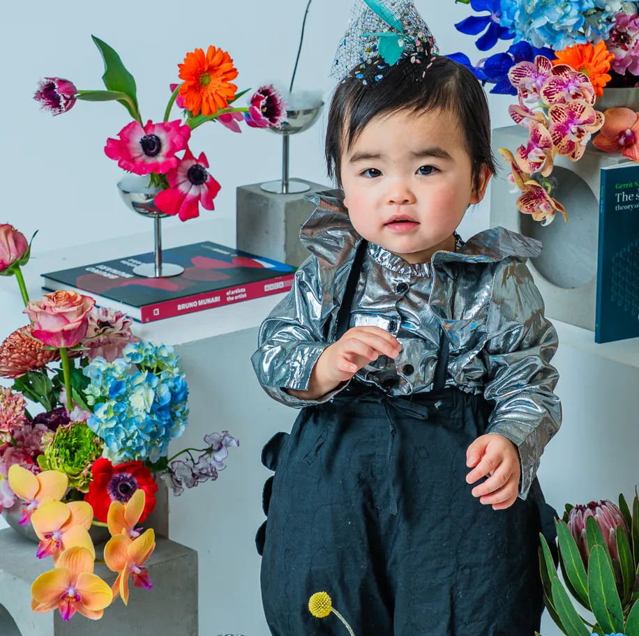 シルバーの衣装に髪飾りを付けて花に囲まれた子どものポートレート