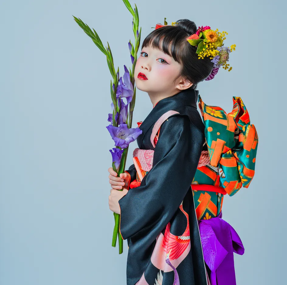 帯と振袖の柄が見える黒い着物姿の七五三の女の子の後ろ姿
