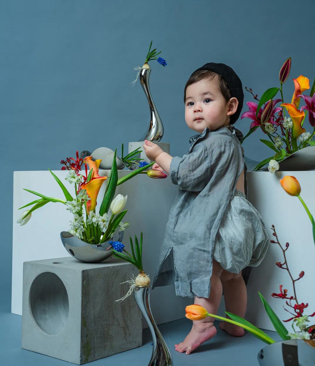 花のアートに囲まれ、チューリップに手を伸ばす赤ちゃん（フローラルフォト作品）