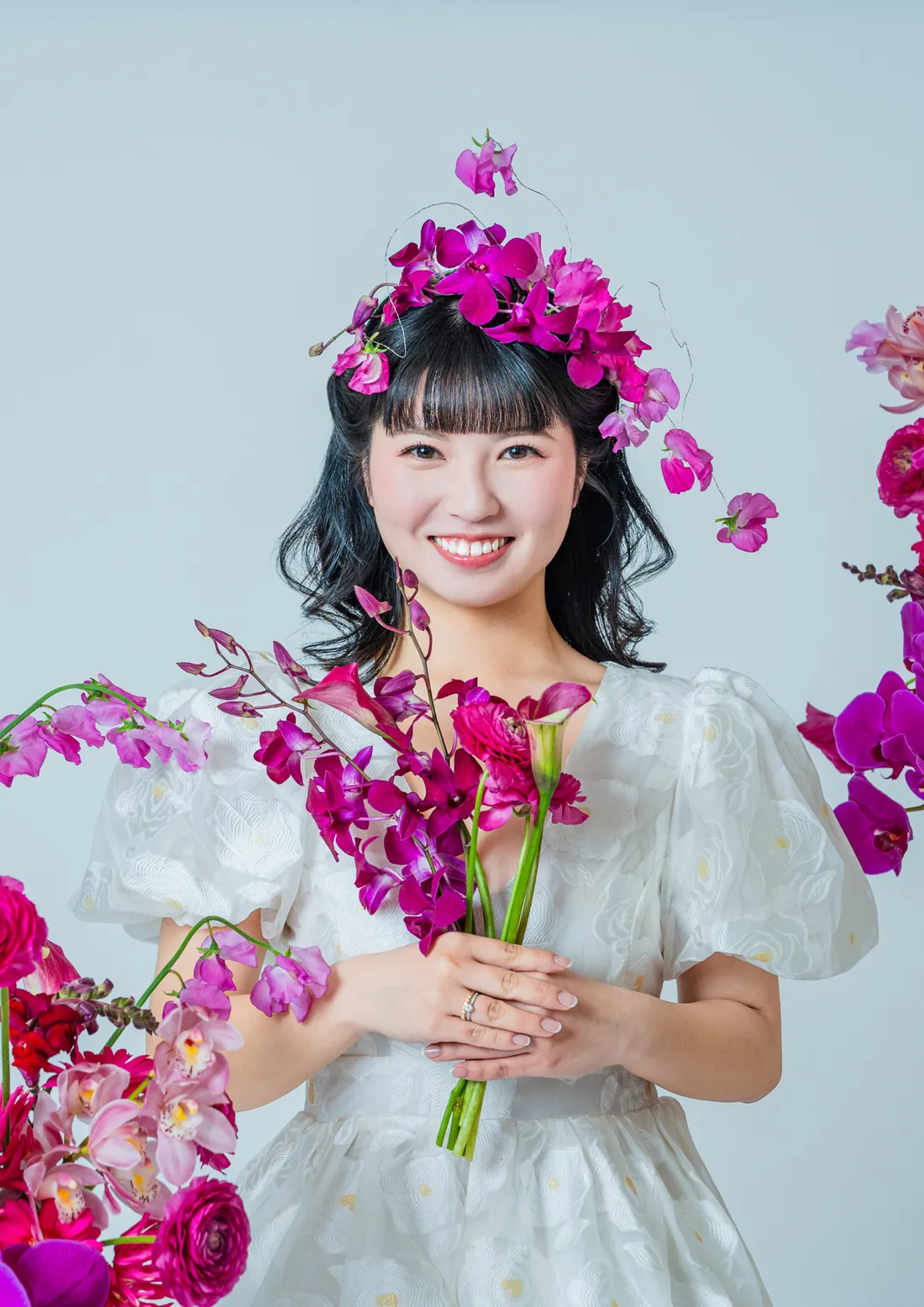 白いドレスと花冠でピンクの花束を抱え微笑む花嫁